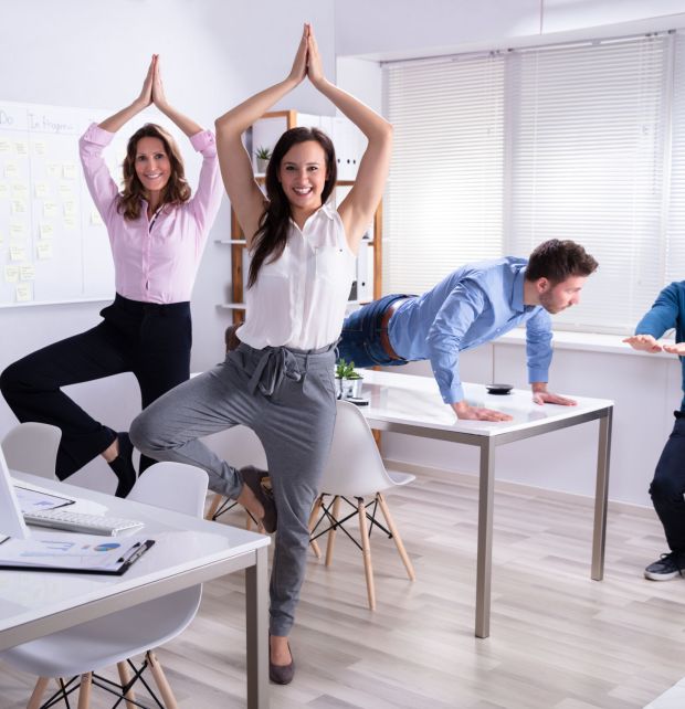 Smiling Young Businesspeople Doing Yoga In Office